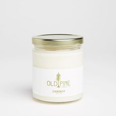 an old pine candle is sitting on a white surface with a gold lid and label