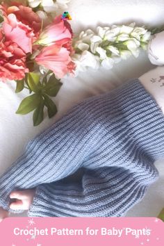 a blue knitted baby blanket next to flowers