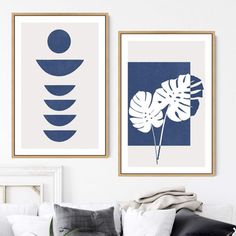 two blue and white paintings hanging on the wall above a couch in a living room