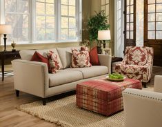 a living room with couches, chairs and ottomans in front of large windows