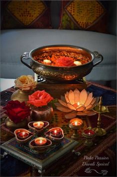 candles and flowers on a table in front of a large pot with water lilies