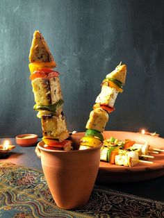 an assortment of food is displayed in a clay bowl on a table next to candles