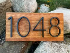 a wooden sign with the number 1048 on it sitting in front of some rocks