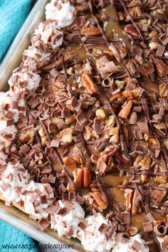 a chocolate dessert with whipped cream and pecans on top is ready to be eaten