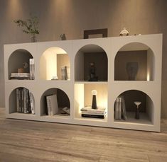 a white shelf filled with lots of books on top of a hard wood floor next to a wall