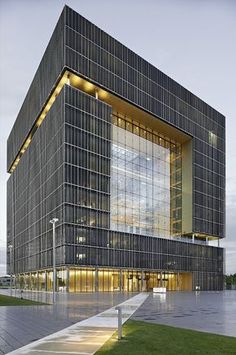 an office building with glass walls and stairs leading up to the front entrance at dusk