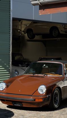 an orange porsche parked in front of a garage