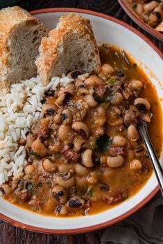 a bowl filled with beans and rice next to two slices of bread on top of a table