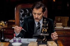 a man sitting at a desk in front of an assortment of miniature figurines