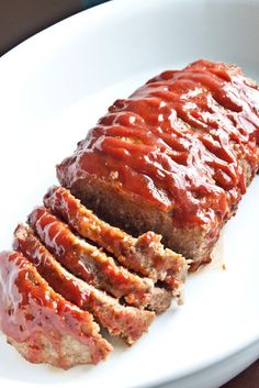 sliced meatloaf on a white plate with sauce drizzled over it