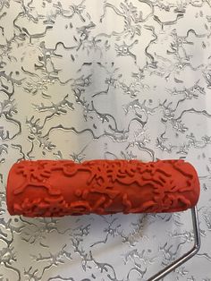 a red object sitting on top of a metal rack next to a wallpapered background