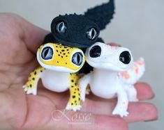 two small toy lizards sitting on top of each other in their human's hand