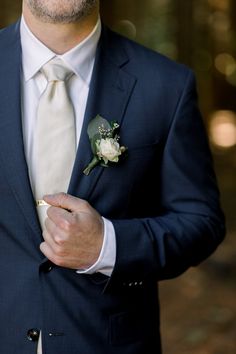 a man wearing a suit and tie with a boutonniere on his lapel