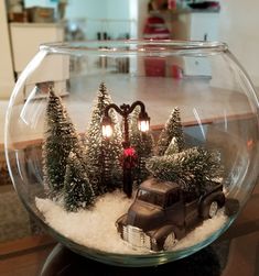 a christmas scene in a fish bowl with an old truck and trees on the snow