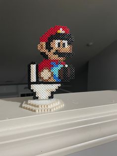 an image of a pixelated mario on top of a toilet in a room with white walls