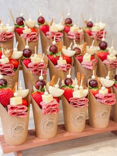 small cups filled with fruit and appetizers on a wooden table in front of a wall