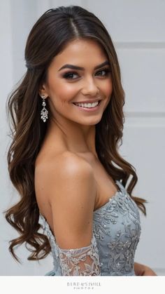 a beautiful young woman with long brown hair wearing a blue dress and smiling at the camera