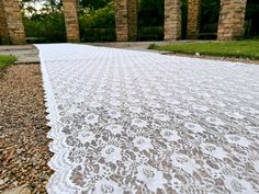 a white lace covered walkway in front of some trees