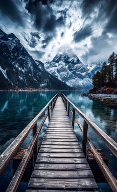 a wooden dock leading to the water with mountains in the background