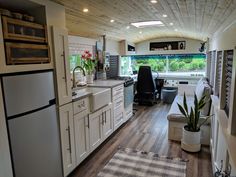 a kitchen with white cabinets and wood flooring next to an open living room area