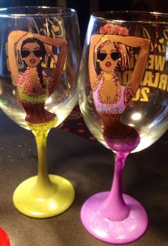 two wine glasses with designs on them sitting next to each other