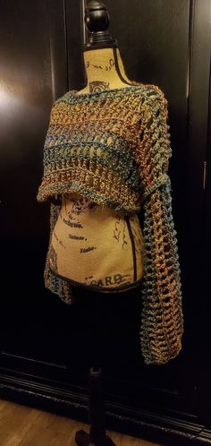 a mannequin wearing a crocheted sweater in front of a black door