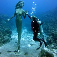 a scuba diver and a statue in the ocean