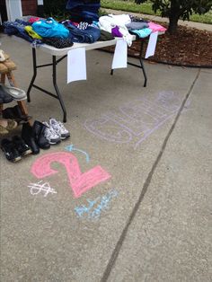 chalk drawings are on the sidewalk next to some shoes and t - shirts for sale