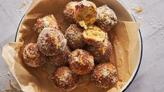 powdered sugar coated doughnuts in a bowl on a white tablecloth with orange zest