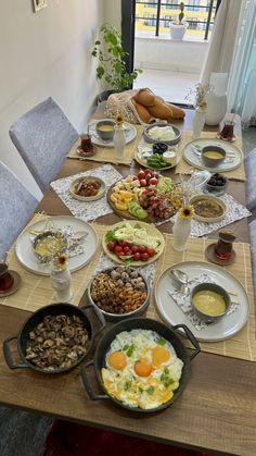 a wooden table topped with lots of plates and bowls filled with different types of food