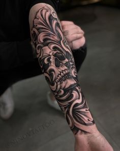 a man's arm with a skull tattoo on it, and an ornate design