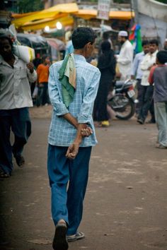 a man is walking down the street with his hand on his hip while wearing a blue suit and green tie