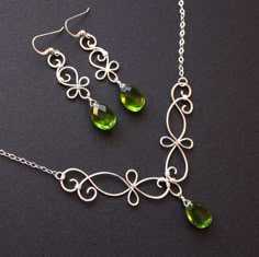 a necklace and earring set with green glass beads on a silver chain, sitting on a black surface