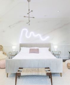 a bedroom with a large bed in the middle and a neon sign above it on the wall