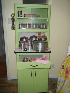 a green cabinet with pots and pans on it