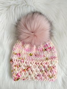 a pink and white knitted hat with a pom - pom on top