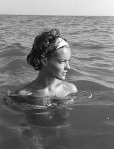 a woman swimming in the ocean wearing a headband and looking off into the distance