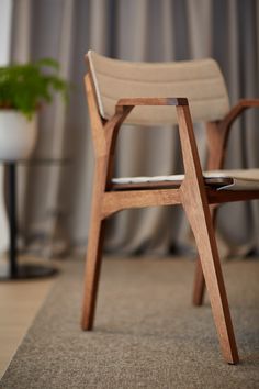 a chair sitting on top of a carpeted floor next to a potted plant