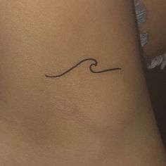 a small wave tattoo on the back of a woman's left leg and neck