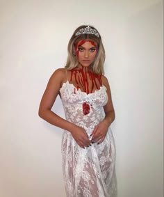 a woman in a white dress with red makeup on her face wearing a tiara