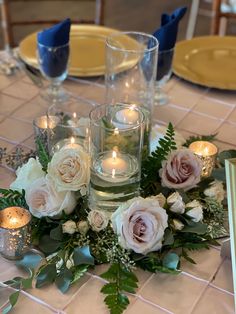 candles are lit on a table with flowers and greenery