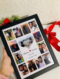 a person holding up a framed photo with pictures on it and a red ribbon around the frame