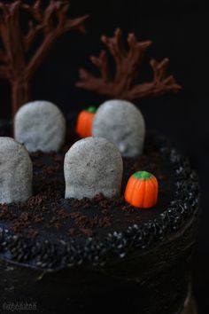 there is a black cake with white frosting and small pumpkins in the middle