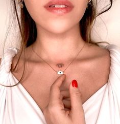 a woman wearing a necklace with an evil eye charm on it's neck and holding her hand in front of her chest