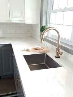 a kitchen with white counter tops and stainless steel sink faucet in the middle