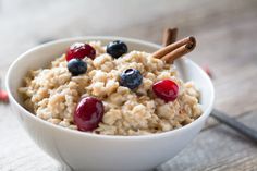 a bowl filled with oatmeal topped with cherries and cinnamon sticks