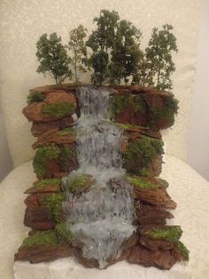 a fake waterfall made out of rocks with trees growing on the top and water running down it