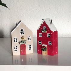 two red and white houses sitting on top of a table next to a potted plant