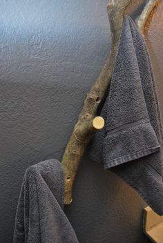 two towels hanging on a wall next to a tree branch with a button in it