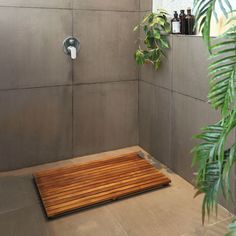 a bathroom with a wooden mat in the middle and plants growing on the wall next to it